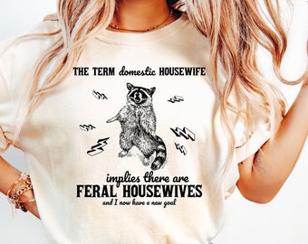 El término ama de casa doméstica implica que hay amas de casa salvajes camisa mapache camisa gráfica camisa divertida nostalgia minimalista