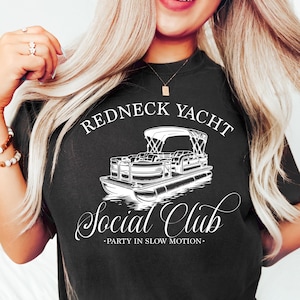 May include: A black t-shirt with a white graphic design of a pontoon boat with the text "Redneck Yacht Social Club - Party in Slow Motion."