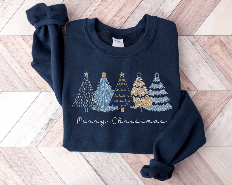May include: A navy blue sweatshirt with a festive design of four stylized Christmas trees in gold and blue with the text "Merry Christmas" underneath.