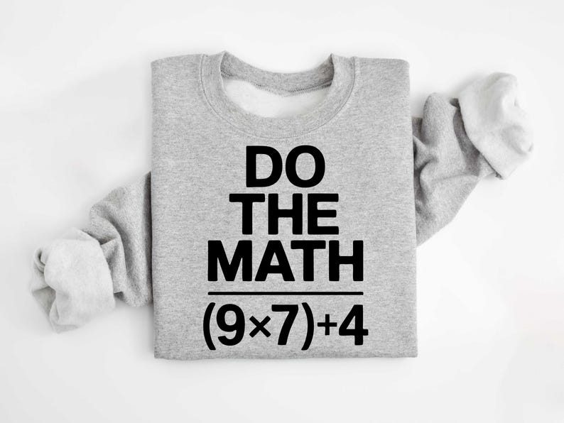 May include: A light gray sweatshirt with the text "DO THE MATH" in bold black letters. Below the text is the equation (9x7)+4. The sweatshirt has long sleeves.