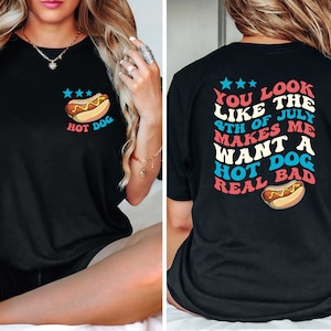 Puede incluir: Camiseta negra con un gr&aacute;fico de un hot dog en la parte delantera y el texto "YOU LOOK LIKE THE 4TH OF JULY MAKES ME WANT A HOT DOG REAL BAD" en la parte posterior.