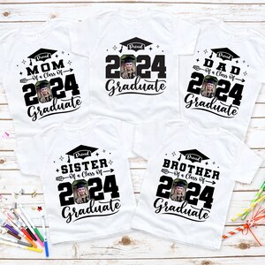Puede incluir: Camisetas blancas con texto negro y una foto de una persona con birrete. Las camisetas dicen "Proud Mom of a Class of 2024 Graduate", "2024 Graduate", "Proud Dad of a Class of 2024 Graduate", "Proud Sister of a Class of 2024 Graduate" y "Proud Brother of a Class of 2024 Graduate".