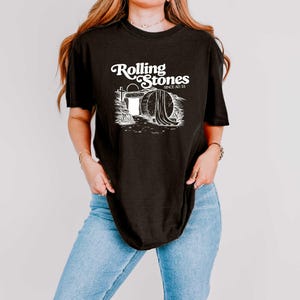 May include: Black t-shirt with a white graphic of a tombstone with the text "Rolling Stones Since AD 33".