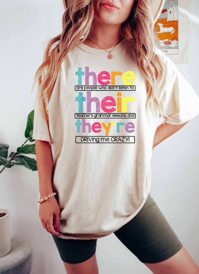 Puede incluir: Camiseta color crema con el texto "there are people who didn't listen to their teacher's grammar lessons, and they're driving me CRAZY!" en letras de colores. La camiseta es de estilo casual.
