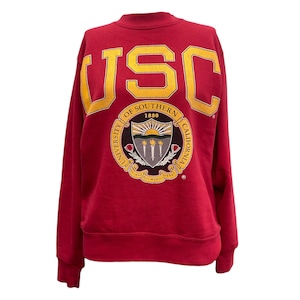 May include: A red long-sleeve sweatshirt featuring the large yellow text USC at the top. Below the text is a circular University of Southern California seal with a shield, torches, and the text University of Southern California 1880.