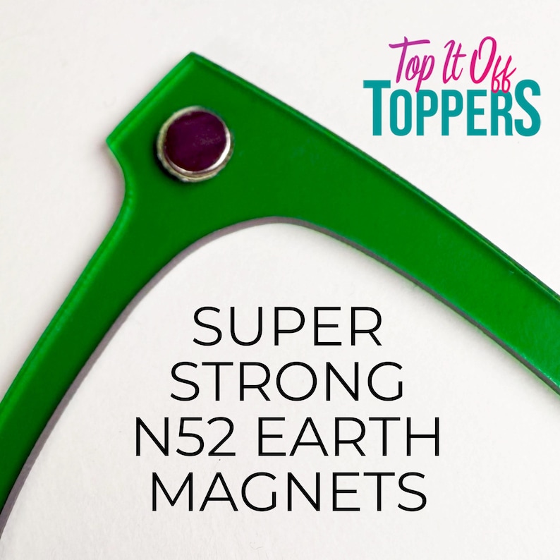 May include: Bright green, angular object with a circular, purple-centered magnet. The text "SUPER STRONG N52 EARTH MAGNETS" is displayed in black, bold font. The upper right corner features the text "Top It Off TOPPERS" in teal and pink.