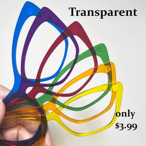 May include: A hand holds a stack of transparent, colorful eyeglasses frames. The frames are in shades of blue, purple, red, green, orange, and yellow. The word "Transparent" is written in black text at the top of the image.