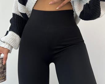 May include: Black high-waisted leggings with a cropped white and black striped sweater.