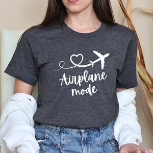 May include: A dark gray t-shirt with a white airplane graphic and the text "Airplane mode" in a cursive font.