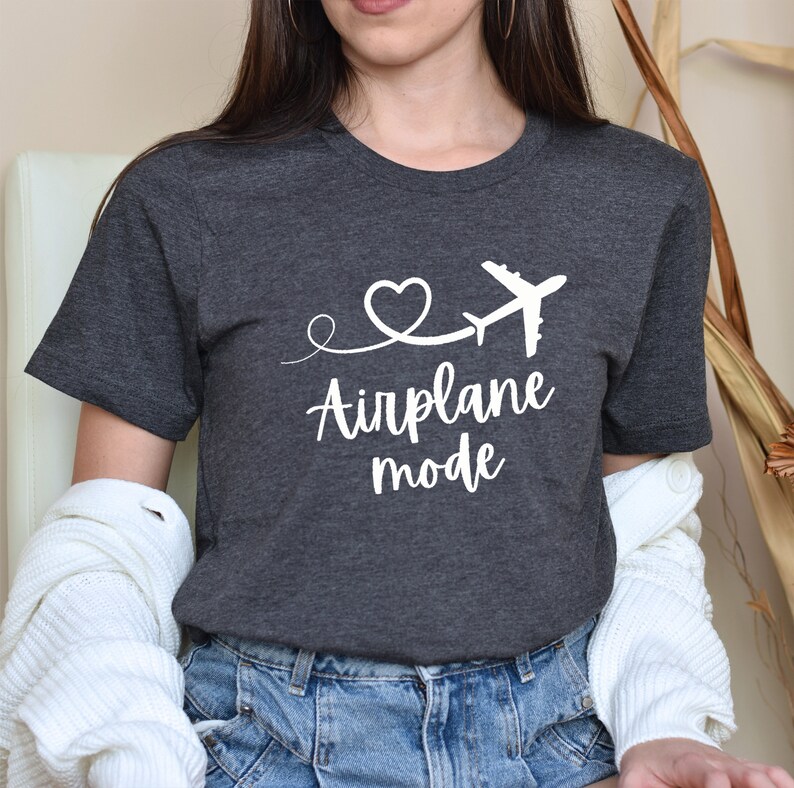 May include: A dark gray t-shirt with a white airplane graphic and the text "Airplane mode" in a cursive font.