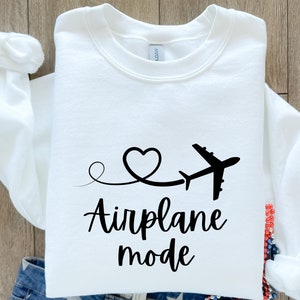 May include: White sweatshirt with a black airplane and heart design. The text "Airplane mode" is printed below the design.