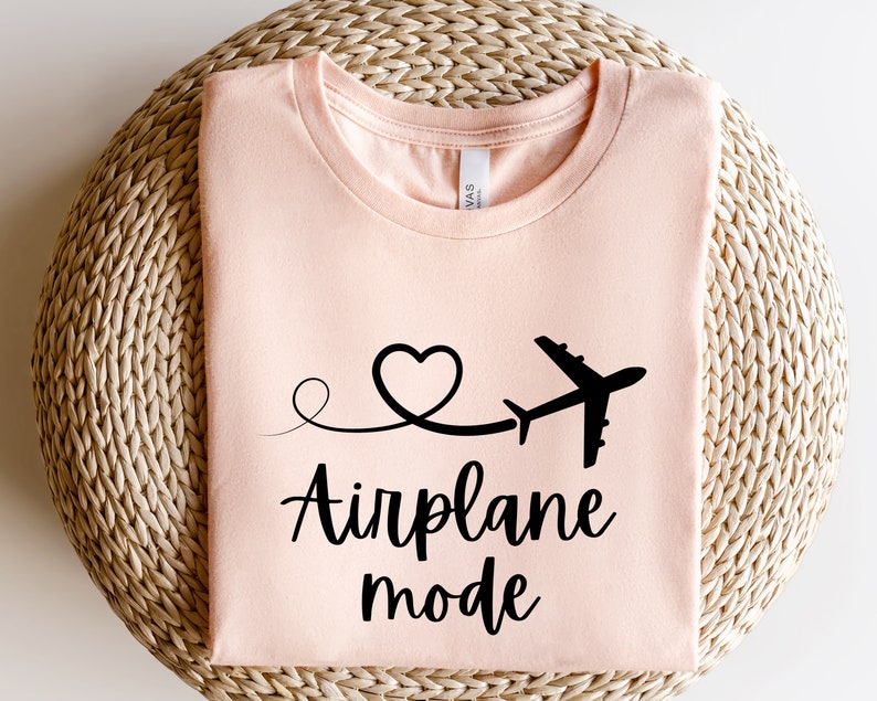 May include: A peach-colored t-shirt with a black airplane graphic and the text "Airplane mode" in a cursive font.