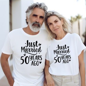 May include: A couple wearing white t-shirts with the text "Just Married 50 Years Ago" printed on them. The couple are standing close together and smiling.