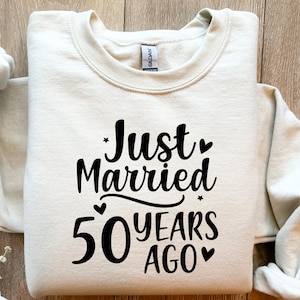May include: A beige sweatshirt with the text "Just Married 50 Years Ago" printed in black.