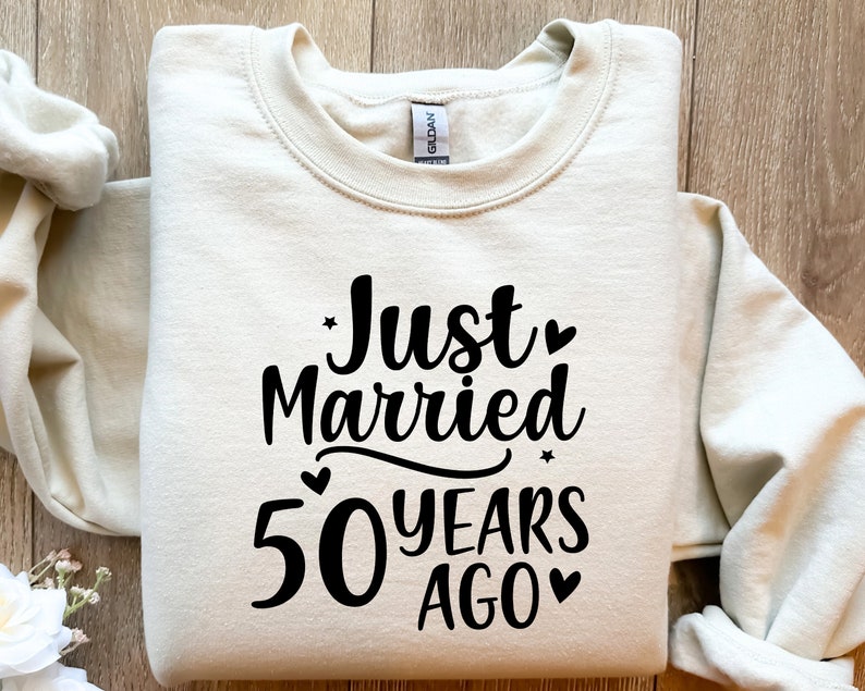 May include: A beige sweatshirt with the text "Just Married 50 Years Ago" printed in black.