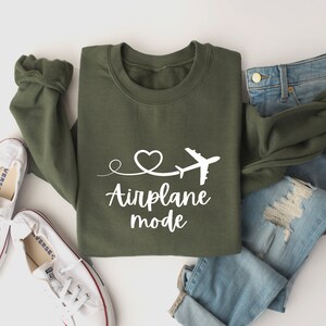 May include: Green sweatshirt with white text that says "Airplane mode" and a small airplane and heart graphic.
