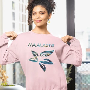 May include: A pink sweatshirt with a flower graphic and the word "Namaste" in colorful letters.