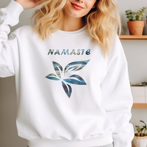 May include: White sweatshirt with a blue and green floral design and the word "Namaste" printed on the front.