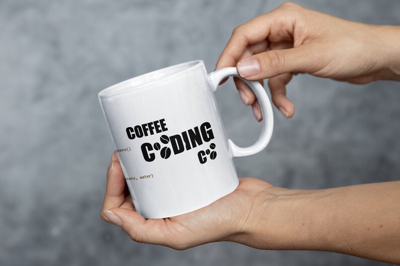 K&ouml;nnte beinhalten: Wei&szlig;e Keramik-Kaffeetasse mit schwarzem Text, der "Coffee Coding C++" lautet, wobei die Buchstaben "o" im Wort "Coding" durch Kaffeekirschen-Symbole ersetzt werden.