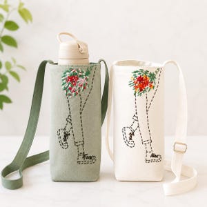May include: Two water bottle carriers, one sage green and one off-white, each with a floral embroidery design and a stitched outline of legs. Both have adjustable straps for carrying. The green carrier holds a beige water bottle.