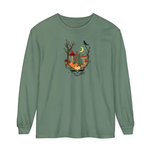 May include: Sage green long-sleeved shirt with a colourful graphic. The graphic features a skull with pumpkins, mushrooms, and a crow under a crescent moon. The design has a whimsical, autumnal theme.
