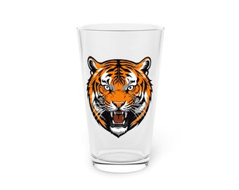 Könnte beinhalten: Ein klares Glas Pint-Glas mit einem Aufdruck eines Tigerkopfes auf der Vorderseite. Der Tiger hat orange und schwarze Streifen auf weißem Hintergrund.