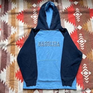 May include: A blue and navy blue hooded sweatshirt with the word "CAROLINA" in white lettering on the front.