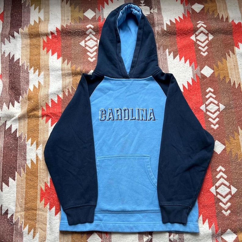 May include: A blue and navy blue hooded sweatshirt with the word "CAROLINA" in white lettering on the front.