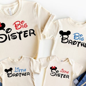 May include: Four cream-colored t-shirts with Mickey Mouse ears and the words "Big Sister", "Big Brother", "Little Brother", and "Little Sister" in black, red, and blue.