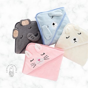 May include: A collection of hooded baby towels in various pastel colors. The towels are shaped like animals, including an elephant, a bear, a cat, and a dog. Each towel features embroidered facial details and ears, creating a soft and playful design.
