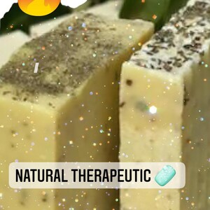 Pode incluir: Duas barras de sabonete terapêutico natural com alecrim e hortelã-pimenta. O sabonete é de cor amarelo claro com manchas verdes e marrons. O texto "NATURAL THERAPEUTIC" está impresso no sabonete.