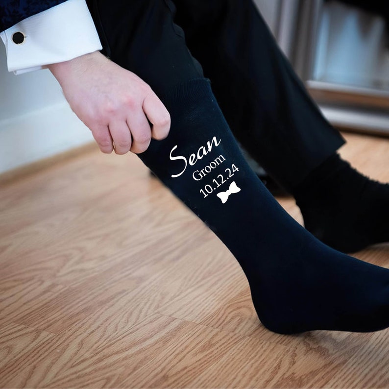Puede incluir: Calcetines negros de vestir con texto blanco que dice "Sean Groom 10.12.24" y un gr&aacute;fico de pajarita.