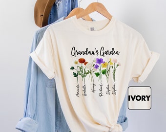 May include: Ivory t-shirt with the text "Grandma's Garden" and a floral design with names written below each flower. The names are Amanda, Bobbie, Henry, Richard, Sophia.