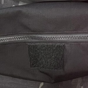 Puede incluir: Una bolsa negra con cremallera y un parche de velcro negro. La bolsa est&aacute; hecha de un tejido resistente y tiene un cierre de cremallera.