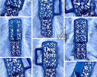 Könnte beinhalten: Eine blaue Reise-Thermoskanne aus Edelstahl mit einem weißen Pfoten- und Knochenmuster. Die Kanne hat einen Griff und steht "Dog Mom" auf der Vorderseite.