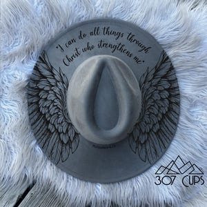 May include: Gray fedora hat with black wing design and the text "I can do all things through Christ who strengthens me." The hat also has the text "Philippians 4:13" and the logo "307 CUPS".