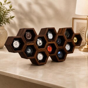 May include: A dark brown wooden watch display stand featuring a honeycomb structure with multiple hexagonal compartments. Each individual hexagonal slot holds a single wristwatch with various dial colours and styles, creating a geometric storage unit.