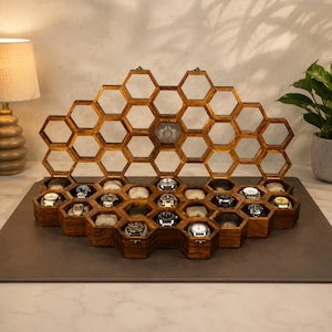 May include: A dark brown wooden watch display case featuring a honeycomb structure with multiple hexagonal compartments. The open-top design includes a raised back panel with empty hexagonal frames and a central emblem with the letter B.