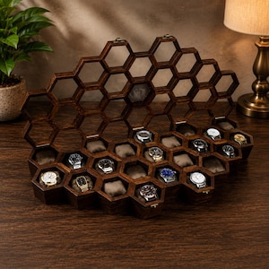 Puede incluir: Un expositor de relojes de madera de color marr&oacute;n oscuro con una estructura en forma de panal y m&uacute;ltiples compartimentos hexagonales. Varios relojes de pulsera con correas y esferas met&aacute;licas descansan sobre cojines beige.