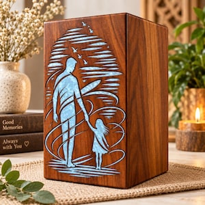 Puede incluir: Una urna rectangular de madera con la silueta tallada de un adulto y un niño tomados de la mano. El diseño recortado está relleno de un material azul claro texturizado, que representa un cielo con pájaros y patrones de viento en espiral.