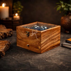 May include: A square wooden watch storage box with a clear glass lid, featuring a visible wood grain pattern, a brass-coloured metal latch, and a small drawer with a round knob. The interior contains blue velvet compartments for holding watches.