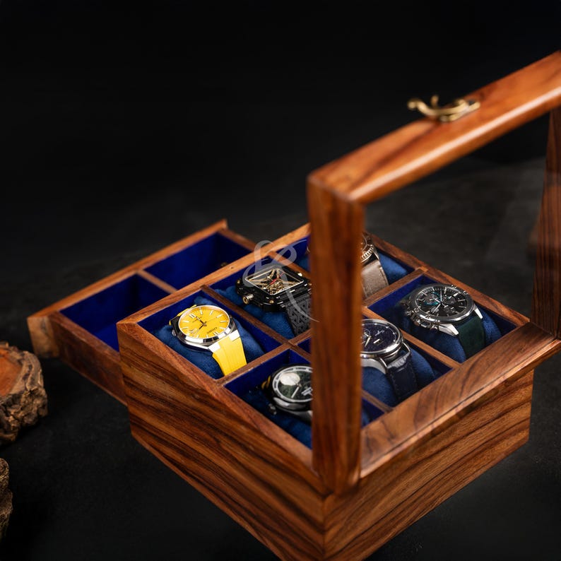 May include: A wooden watch storage box with a hinged glass lid and a pull-out drawer. The interior features multiple compartments lined with blue velvet, each holding a wristwatch. The watches include one with a bright yellow strap and face.