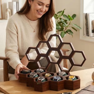 Puede incluir: Un expositor de relojes de madera de color marr&oacute;n oscuro con un dise&ntilde;o inspirado en un panal de abejas y m&uacute;ltiples compartimentos hexagonales. La estructura abierta contiene varios relojes de pulsera con esferas de colores variados y correas met&aacute;licas, dispuestos en los huecos de madera.