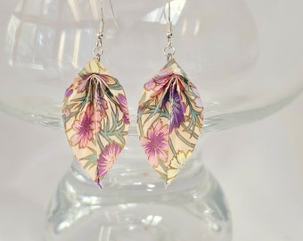 May include: A pair of floral origami earrings with a cream background and pink and purple flowers. The earrings are hanging from silver hooks.