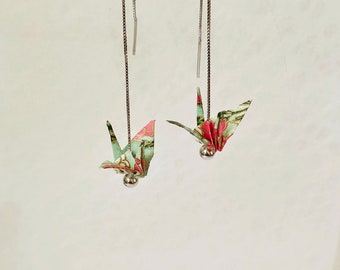 May include: A pair of silver dangle earrings with origami cranes made from patterned paper. The cranes are green, pink, and gold.