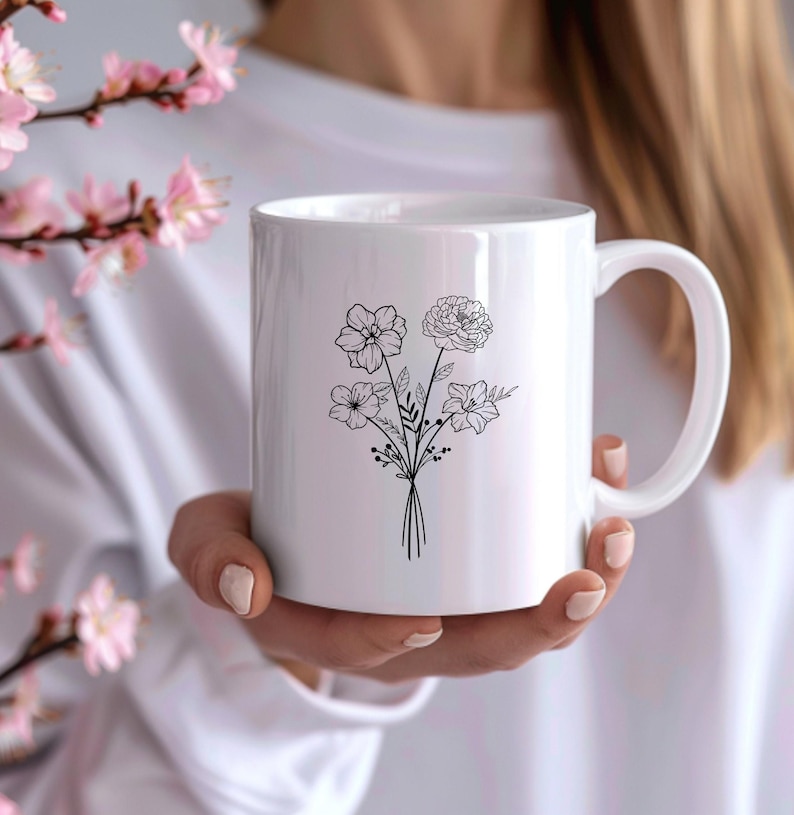 May include: White ceramic mug with a black line drawing of a bouquet of flowers. The flowers are stylized and have a simple design.