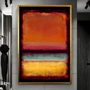 May include: Abstract artwork in a gold frame. The painting showcases a layered arrangement of colours, including orange, red, blue, and yellow. The painting has a textured look, with visible brushstrokes. The artwork is displayed on a grey wall.