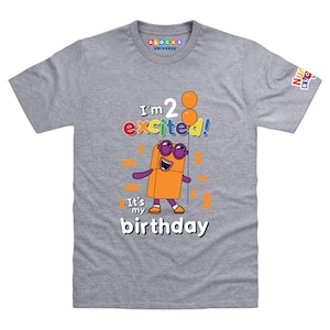 May include: A heather gray short-sleeve t-shirt featuring a graphic of an orange rectangular character wearing purple sunglasses. The text reads I'm 2 excited! It's my birthday, accompanied by two orange balloons and small orange square accents.