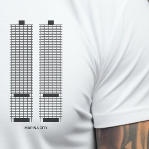 May include: White t-shirt with a black graphic of the Marina City towers in Chicago. The graphic is a simple outline of the buildings with black windows.