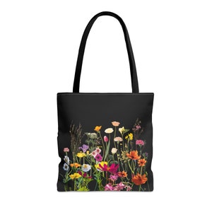 Op de afbeelding: Zwarte tote bag met een kleurrijke bloemenprint met verschillende bloemen, waaronder roze, gele, oranje en rode.